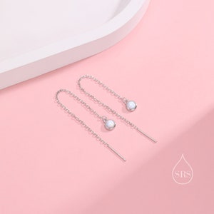 May include: A pair of silver chain earrings with small white opal stones at the end of each chain.