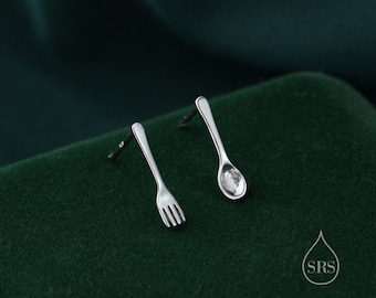 May include: A pair of silver earrings, one shaped like a fork and the other shaped like a spoon.