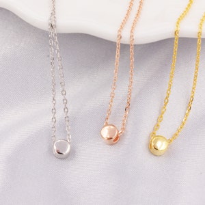 Può includere: Tre delicate collane con un solo ciondolo rotondo. Le collane sono d'argento, oro rosa e oro.
