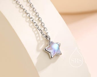 May include: A silver-toned metal chain necklace featuring a small, five-pointed star pendant. The star pendant contains a smooth, iridescent, light-reflecting stone that displays soft blue and purple hues. The necklace has a delicate link design.