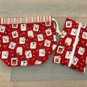 May include: A red fabric drawstring pouch and a matching rectangular zippered pouch, both featuring a repeating pattern of Christmas-themed mason jars containing snowmen, reindeer, Santa Claus, and holiday houses on a red background.