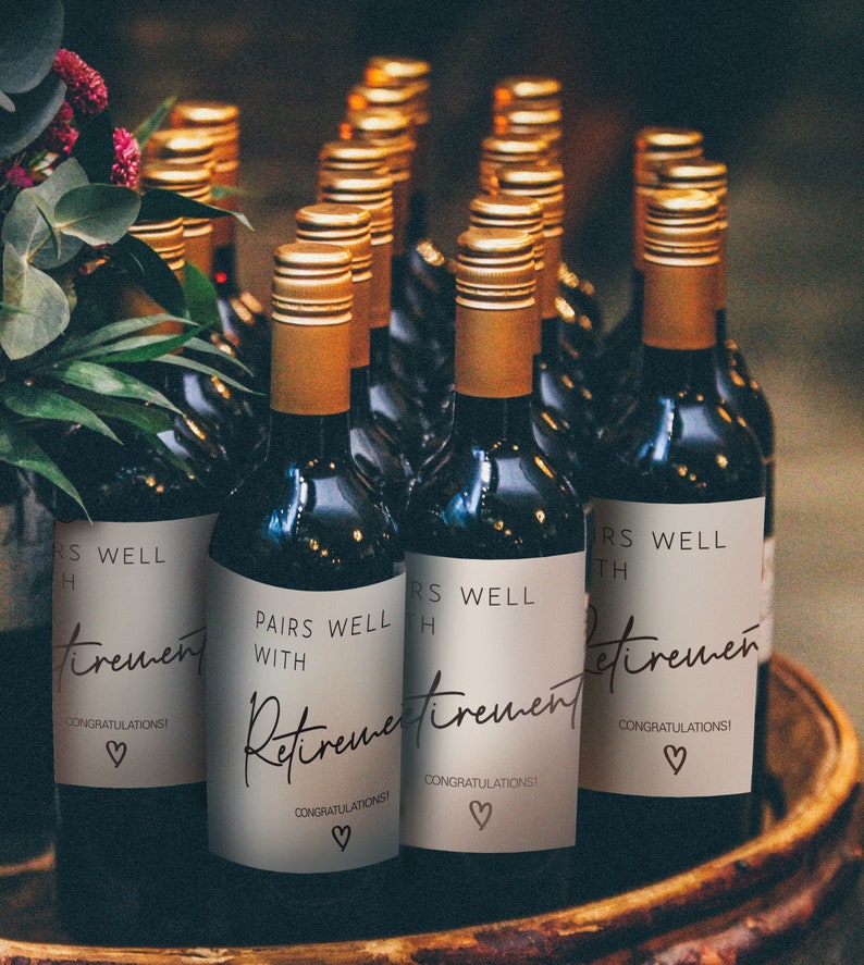Peut inclure: Un groupe de bouteilles de vin avec des &eacute;tiquettes personnalis&eacute;es qui disent "Pairs Well With Retirement" et "Congratulations!" dans une police d'&eacute;criture manuscrite. Les &eacute;tiquettes sont beiges avec du texte brun et un petit symbole de c&oelig;ur.