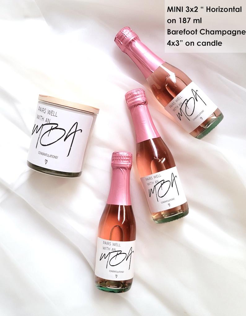 May include: Three mini bottles of pink champagne with white labels that say "Pairs well with an MBA" and "Congratulations!"  A white candle with a wooden lid and a label that says "Pairs well with an MBA" and "Congratulations!"