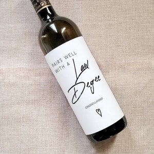 May include: A white wine bottle with a label that says "Pairs well with a Law Degree" and "Congratulations!" with a heart symbol.