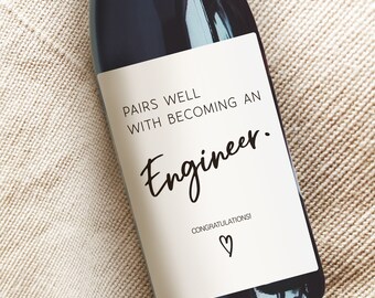 May include: A white wine bottle label with black text that reads "Pairs well with becoming an Engineer. Congratulations!" with a heart symbol.