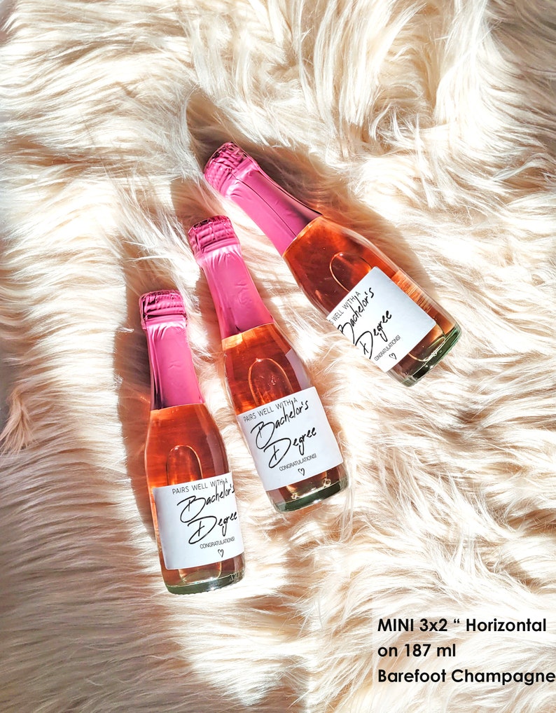 K&ouml;nnte beinhalten: Drei Mini-Flaschen rosa Champagner mit Etiketten, auf denen "Pairs well with a Bachelor's Degree" und "Congratulations" steht. Die Flaschen befinden sich auf einer flauschigen wei&szlig;en Oberfl&auml;che. Der Text "MINI 3x2" Horizontal auf 187 ml Barefoot Champagne" befindet sich unter den Flaschen.