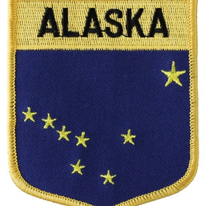 May include: A blue and gold embroidered patch with the word "ALASKA" in black lettering and a constellation of eight yellow stars.