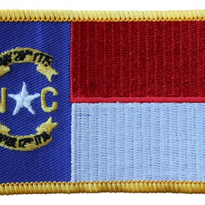May include: A blue and white embroidered patch with a gold border. The patch features a white star and the letters "NC" in gold. The patch also features a gold ribbon with the words "May 20th 1775" and "April 12th 1776" on it.