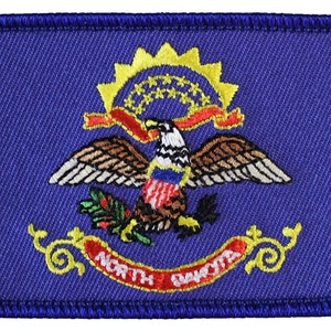 May include: Embroidered patch of the North Dakota state flag. The flag is blue with a gold sunburst with 13 stars, a red ribbon, a golden eagle with a red, white, and blue shield, and a green sprig of wheat. The words "NORTH DAKOTA" are written in red and gold.