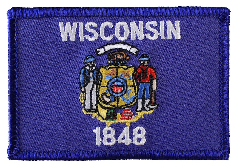 Op de afbeelding: Een blauwe geborduurde patch met het staatszegel van Wisconsin. Het zegel toont een schild met een blauwe achtergrond en een witte vogel, een boer met een hooivork en een matroos met een anker. De tekst "WISCONSIN" staat boven het zegel en "1848" onder het zegel.