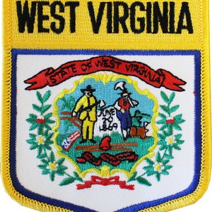 May include: A yellow and blue embroidered patch with the words "West Virginia" at the top and the state seal in the center. The seal features a red ribbon with the words "State of West Virginia" and two men standing on a rock with a tree behind them.