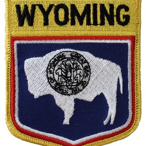 May include: Yellow and blue embroidered patch with the word "WYOMING" in black lettering at the top and a white silhouette of a buffalo with the state seal inside on a blue background.