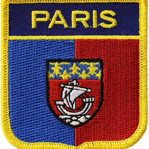 May include: A blue and red embroidered patch with a yellow border. The patch features the word "PARIS" in yellow lettering and a coat of arms with a ship and stars.