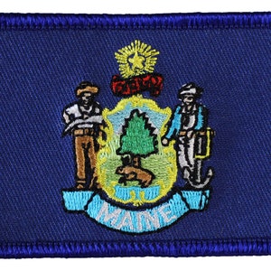 May include: Embroidered patch featuring the state seal of Maine. The seal depicts a pine tree, a moose, a farmer, a sailor, and a ship's anchor. The words "DIRIGO" and "MAINE" are displayed on the seal.