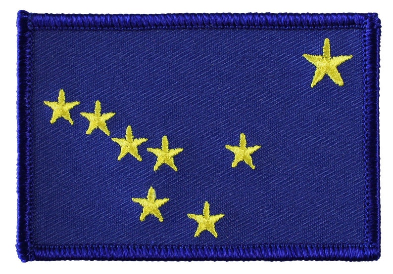 Może przedstawiać: Naszywka z niebieskiego materiału z ż&oacute;łtym haftem przedstawiającym konstelację Wielkiej Niedźwiedzicy, znaną r&oacute;wnież jako Wielki W&oacute;z. Naszywka ma niebieski brzeg z białymi szwami.