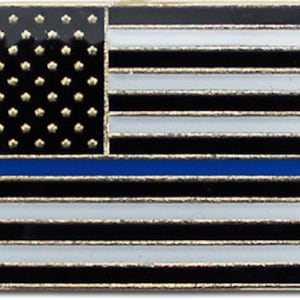 May include: A rectangular pin featuring a stylized American flag design. The flag has a black field of stars, black and white stripes, and a blue line. The pin has a gold-colored border.