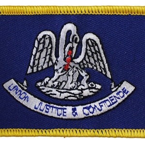 May include: Embroidered patch featuring the state flag of Louisiana. The patch is blue with a white pelican with a red spot on its chest. The pelican is holding a fish in its beak. The words "Union Justice & Confidence" are written on a white banner below the pelican.