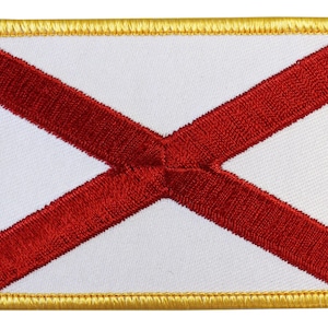 May include: A white patch with a red cross embroidered on it. The patch has a gold border.