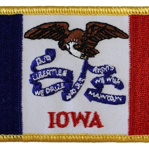 May include: Embroidered patch of the Iowa state flag. The flag features a blue field, a white field with an eagle and a blue ribbon with the words "Our Liberties We Prize And Our Rights We Will Maintain", and a red field. The word "IOWA" is embroidered in red on the white field.