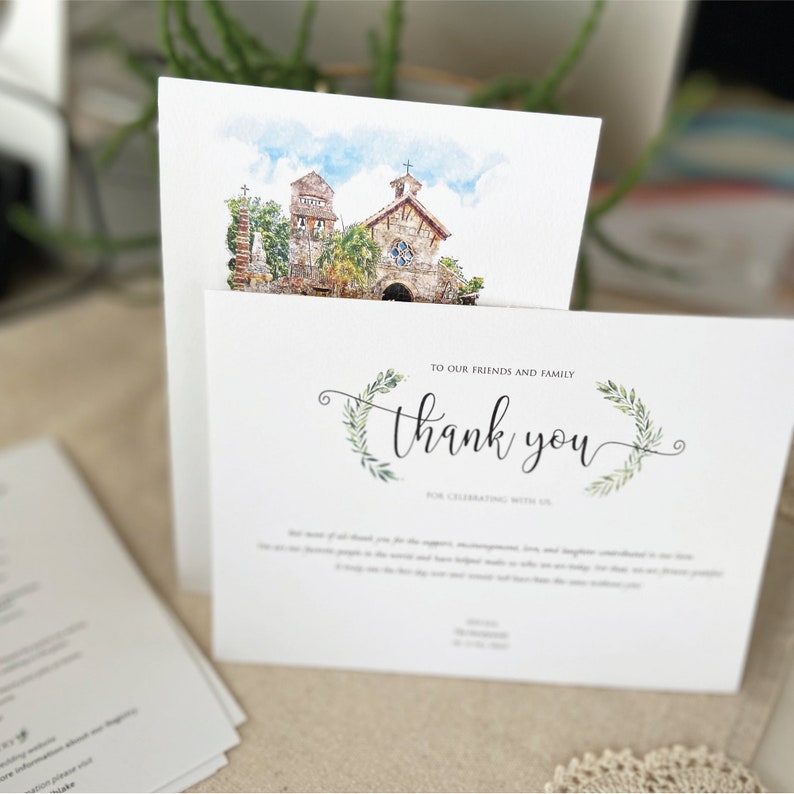 May include: A watercolor illustration of a church with a green leafy wreath and the text "Thank you" for celebrating with us. This is a thank you card for a wedding or other special event.