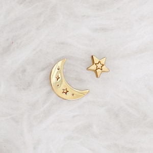 Peut inclure: Breloque en or en forme de croissant de lune et d'étoile sur fond blanc. La lune a un motif d'étoile à l'intérieur.
