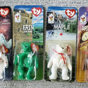 May include: Four Ty Beanie Babies from the '90s, each representing a different country. The bears are named Glory, Erin, Maple, and Britannia. Each bear is wearing a small tag with the Ty logo and the bear's name.