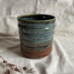 May include: A ceramic vase with a blue, green, and brown glaze. The vase has a textured, wavy design.