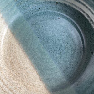 May include: A ceramic bowl with a blue and white glaze. The bowl has a wide, shallow shape and a smooth, rounded rim.
