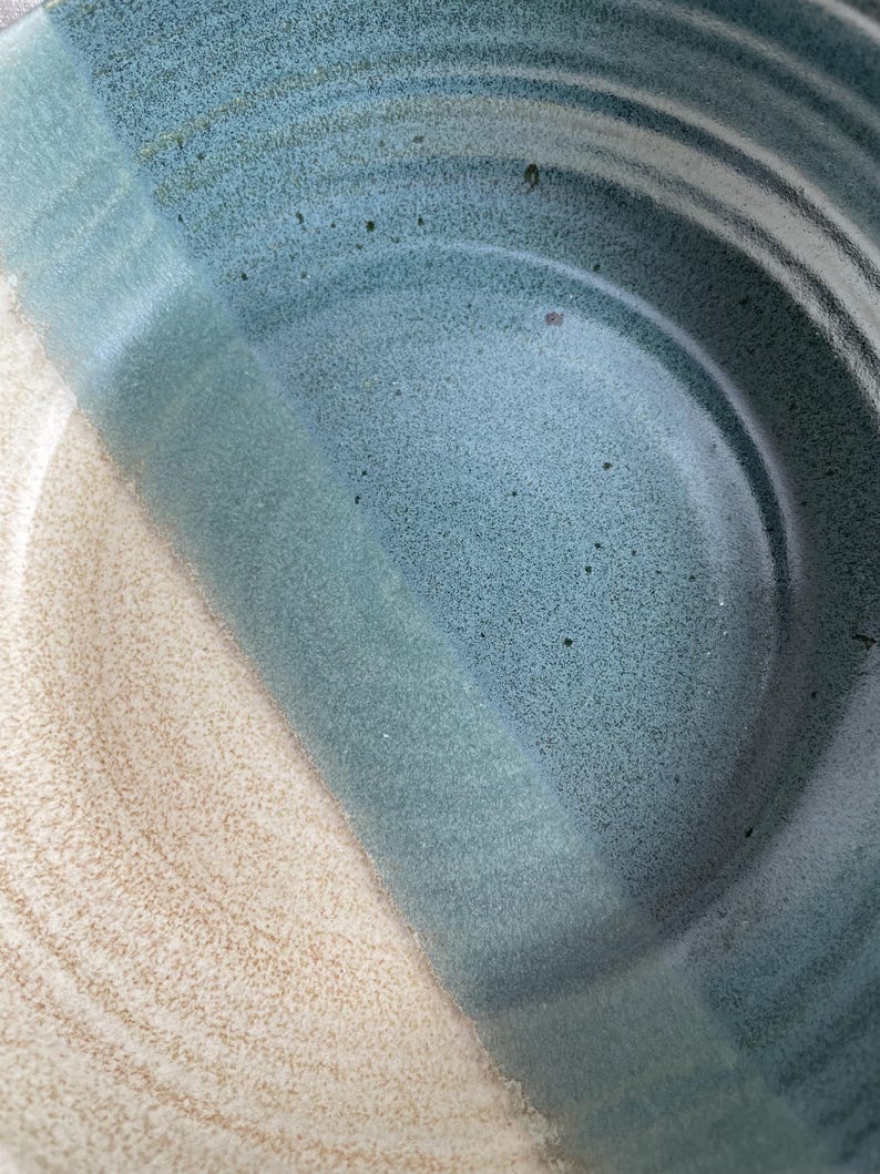 May include: A ceramic bowl with a blue and white glaze. The bowl has a wide, shallow shape and a smooth, rounded rim.