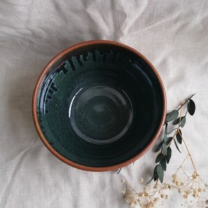 May include: A large, deep bowl with a dark green glaze and a brown rim. The bowl has a speckled, textured surface.