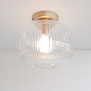 May include: A clear glass ceiling light fitting with a gold metal base and ribbed glass shade.