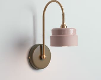 May include: A brass wall sconce with a curved arm and a two-tiered pink ceramic shade.