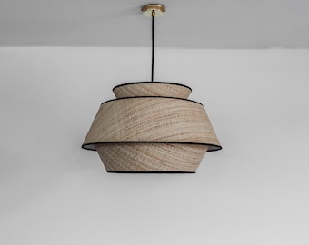 May include: A woven pendant light with a natural beige shade and black trim. The light has a layered design with three tiers.