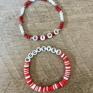 May include: Two beaded bracelets with red and white beads. One bracelet spells "O-H-I-O" and the other spells "BUCKEYES".
