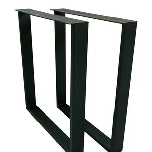 May include: Two black metal table legs with a rectangular frame. The legs are made of sturdy metal and have a black powder coat finish.