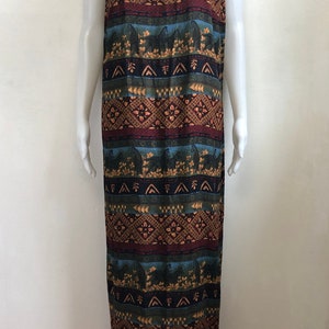May include: A sleeveless maxi dress with a colorful geometric pattern in shades of brown, blue, green, and red. The pattern features stylized arrows, diamonds, and floral motifs.