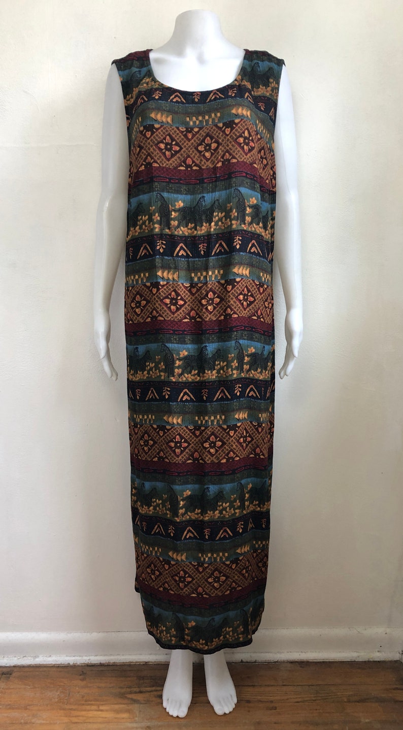 May include: A sleeveless maxi dress with a colorful geometric pattern in shades of brown, blue, green, and red. The pattern features stylized arrows, diamonds, and floral motifs.