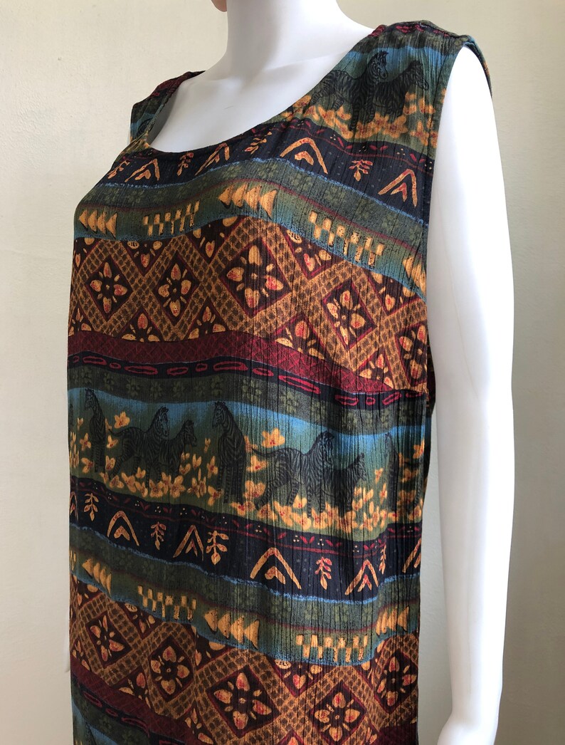 May include: A sleeveless dress with a colorful, geometric pattern featuring zebras and floral motifs. The dress is made of a soft, flowing fabric and has a relaxed fit.