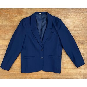 Può includere: Un blazer blu navy con una chiusura a bottone singolo e due tasche. Il blazer ha una vestibilità classica e sartoriale.