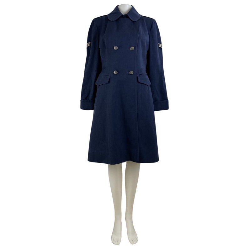 Pu&ograve; includere: Un cappotto blu navy doppiopetto con colletto e due tasche. Il cappotto ha bottoni argentati e strisce argentate sulle maniche.