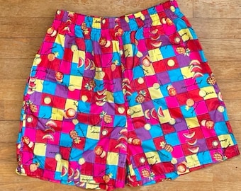May include: A pair of colourful shorts with a checkered pattern featuring various fruits such as watermelon, pineapple, and lemons. The shorts are made from a lightweight fabric and have an elastic waistband.