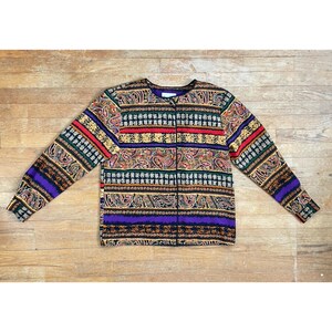 May include: A long-sleeved button-up shirt with a paisley and geometric pattern in shades of brown, red, purple, and black.