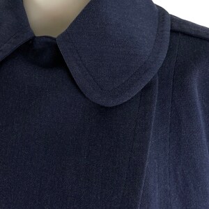 Pu&ograve; includere: Primo piano di una giacca blu navy con colletto e un colletto leggermente appuntito.