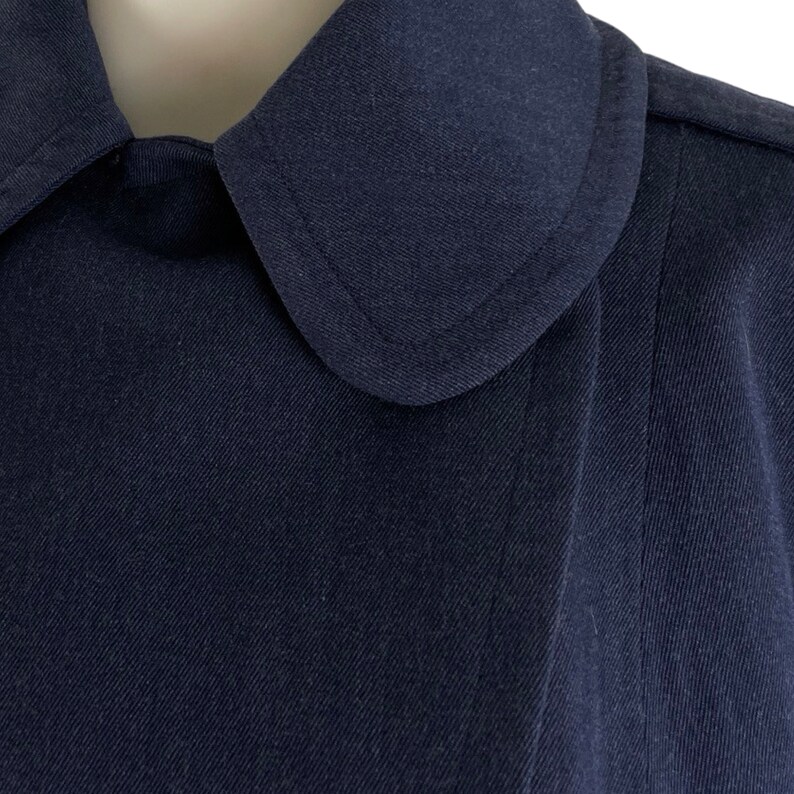 Pu&ograve; includere: Primo piano di una giacca blu navy con colletto e un colletto leggermente appuntito.
