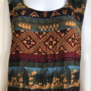 May include: A sleeveless, multi-colored dress with a geometric pattern featuring zebras, flowers, and abstract shapes. The dress is made of a soft, textured fabric.