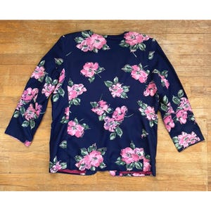K&ouml;nnte beinhalten: Ein marineblauer Blazer mit einem pink- und gr&uuml;nfarbigen Blumendruck. Der Blazer hat lange &Auml;rmel und einen Knopfverschluss.