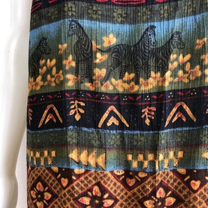 May include: A long, flowing skirt with a colorful, tribal-inspired print featuring zebras, geometric patterns, and floral motifs. The skirt is made of a soft, textured fabric and has a flowing silhouette.