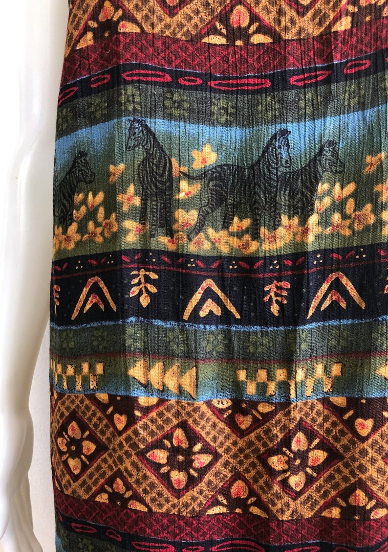 May include: A long, flowing skirt with a colorful, tribal-inspired print featuring zebras, geometric patterns, and floral motifs. The skirt is made of a soft, textured fabric and has a flowing silhouette.