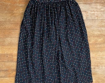 Könnte beinhalten: Ein marineblauer Rock mit einem Polka-Dot-Muster. Der Rock hat weiße, rote und blaue Punkte. Der Rock hat einen gerafften Bund und reicht bis zur Wade.