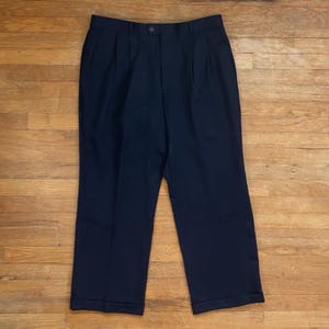 May include: A pair of dark blue pleated pants with a button closure and cuffed hems.